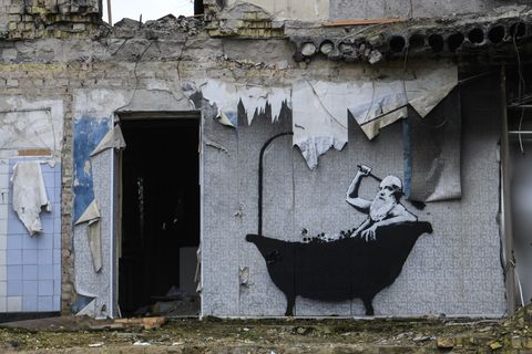 new graffiti by banksy on the wall of a destroyed residental buildings in the towns near kyiv