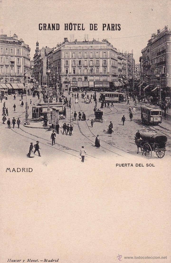 a group of people walking on a street with a horse drawn carriage