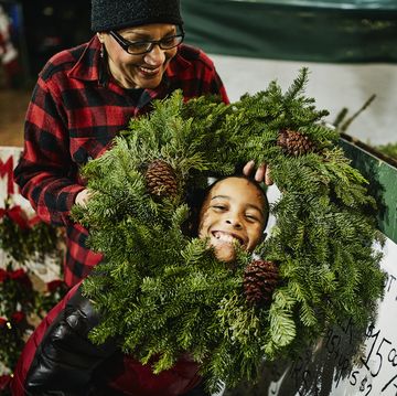 grandmother holding christmas wreath around smiling grandson