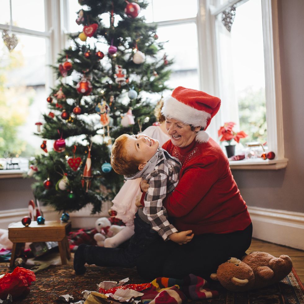 grandmother playing with her grandson in front of the christmas tree