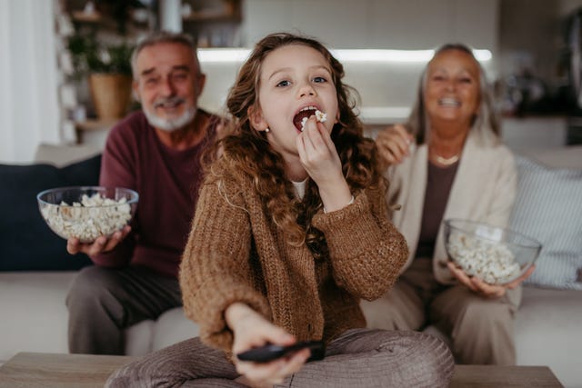 grandparents watching tv with their granddaughter