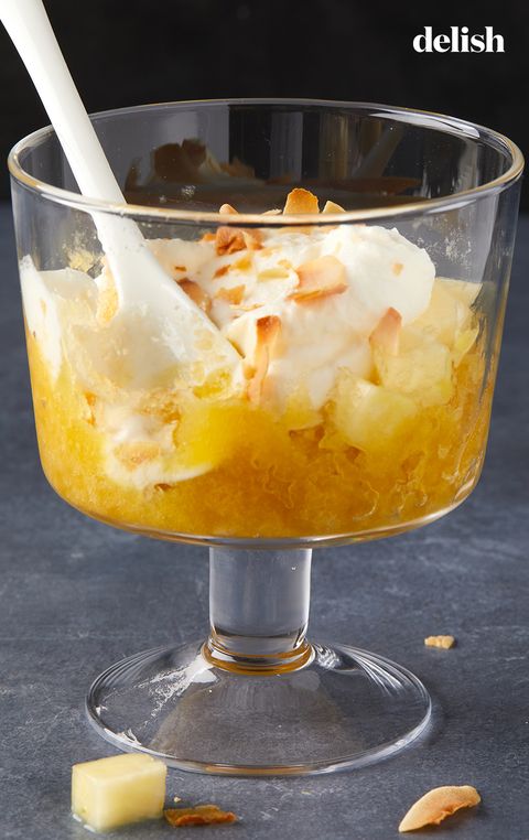 glass of pineapple granita topped with whipped cream and toasted coconut flakes