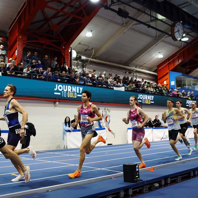 professional runners in a line on a blue indoor track