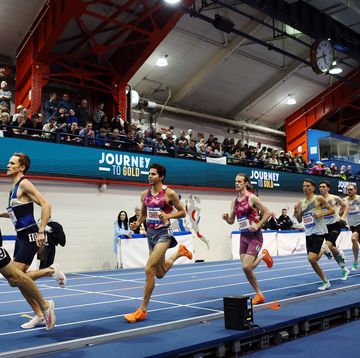 professional runners in a line on a blue indoor track