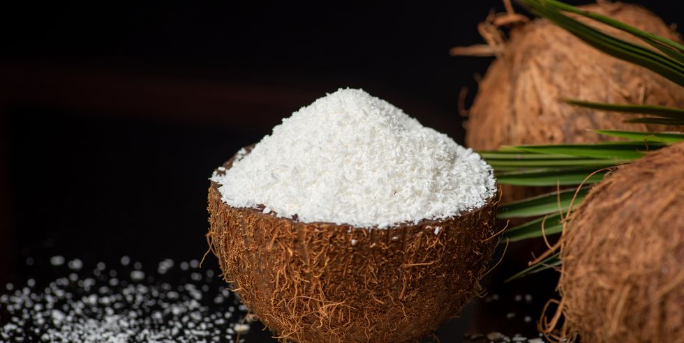 grated coconut powder falling out of a coconut shell with copy space