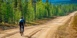 Gravel road cyclist heading on a long downhill stretch in the Finnish Lapland