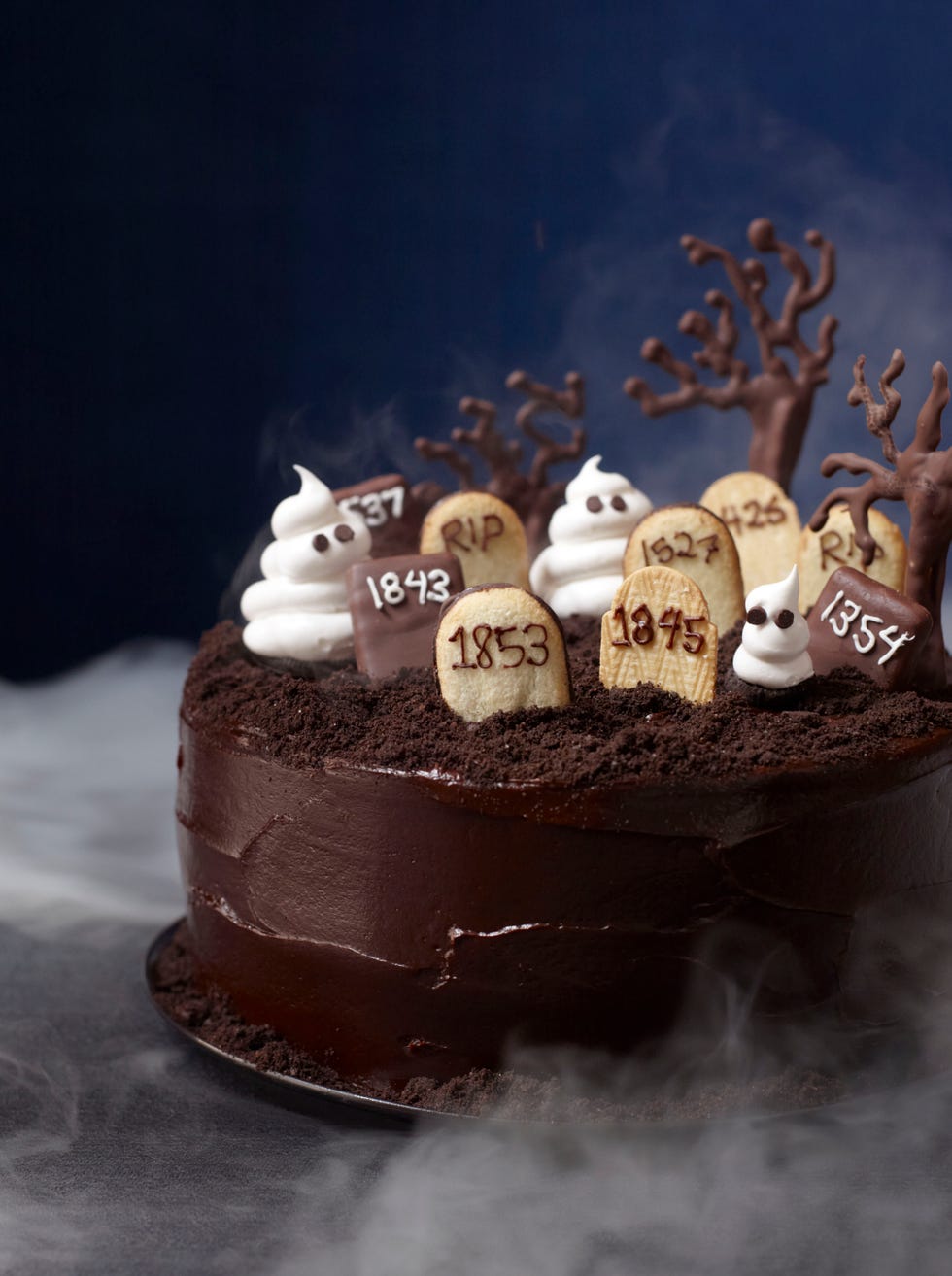 a round chocolate cake with tombstone cookies on top