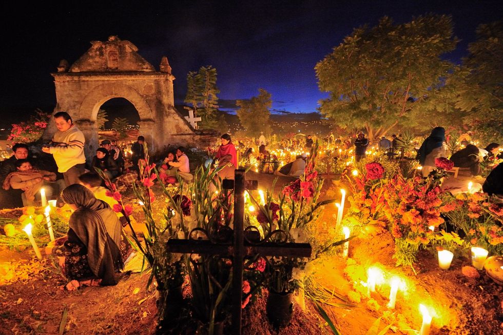 Bloemen en kaarsen brengen sfeer tijdens een wake ter ere van Da de los Muertos op een kerkhof in de Mexicaanse stad Oaxaca