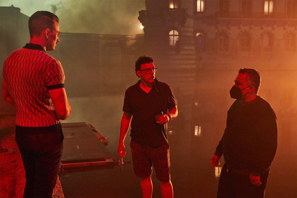 in a behind the scenes photo from netflix movie the gray man on netflix, chris evans, dressed as his character lloyd hansen, talks to the filmmakers, anthony and joe russo
