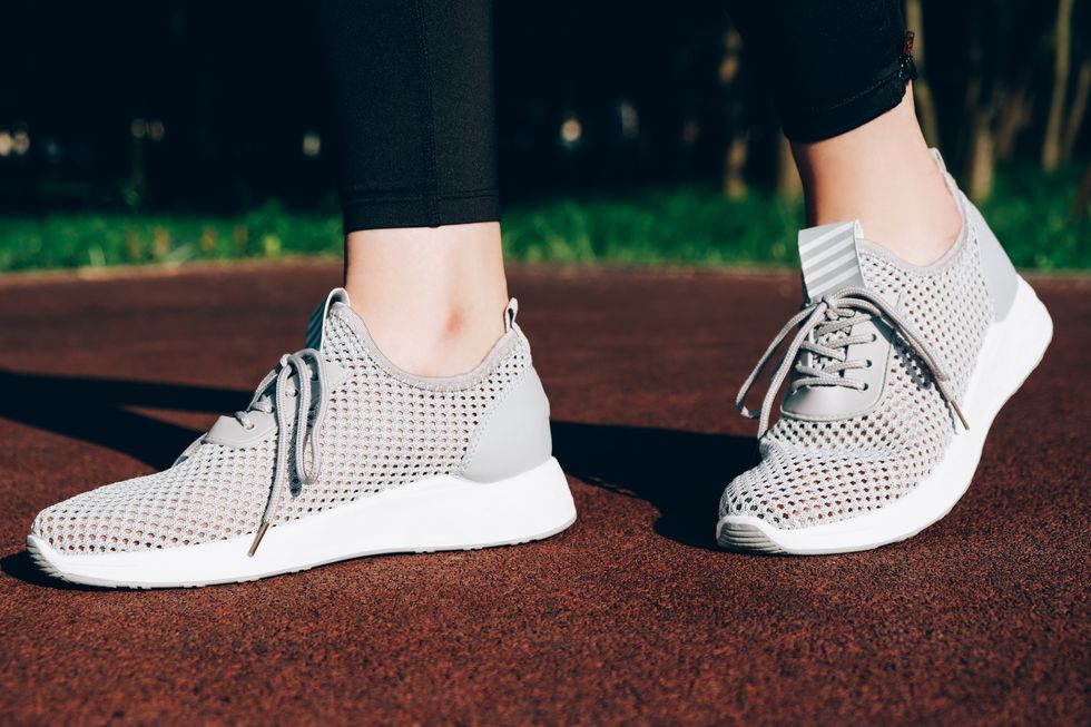 gray woman sneakers on a sportsground with sun