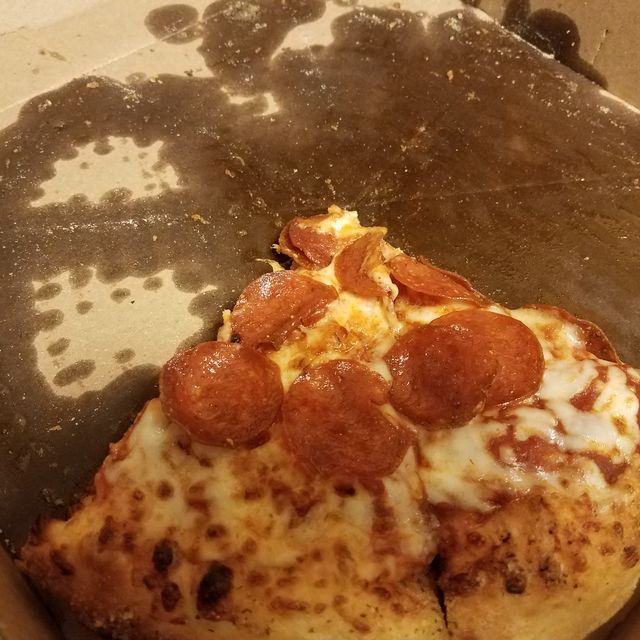 greasy slices of pepperoni pizza in pizza box