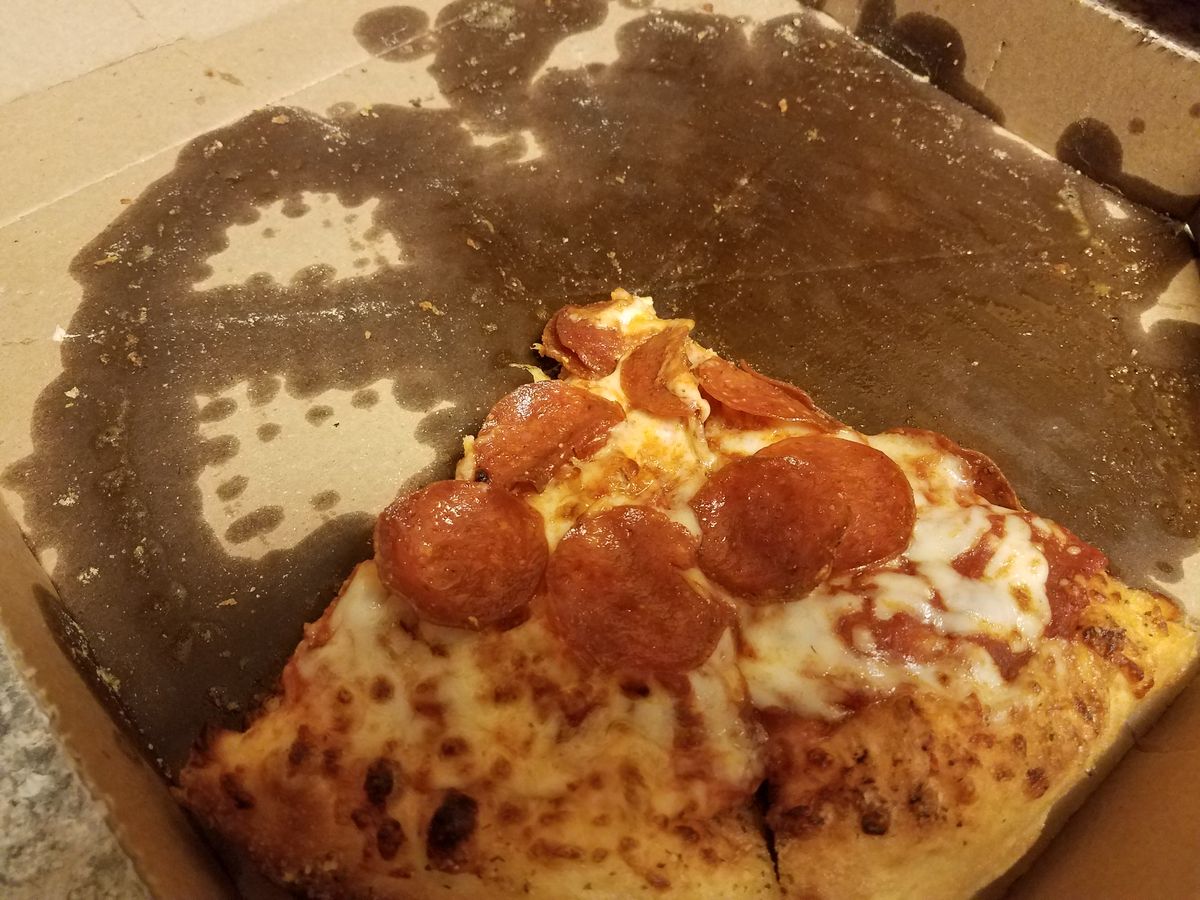 greasy slices of pepperoni pizza in pizza box