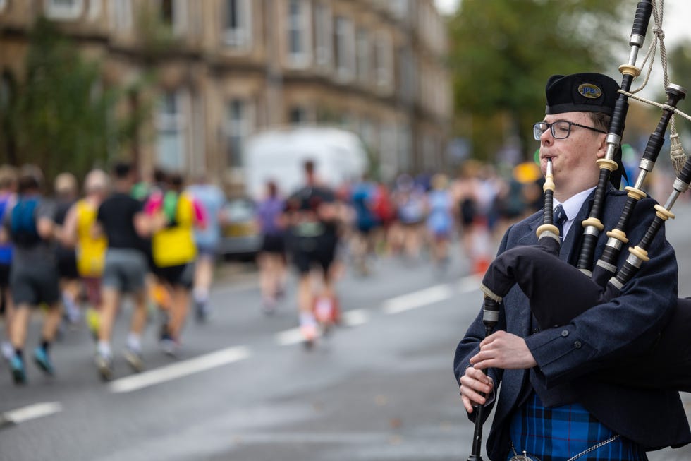 a bagpipe player supporting runners in a race