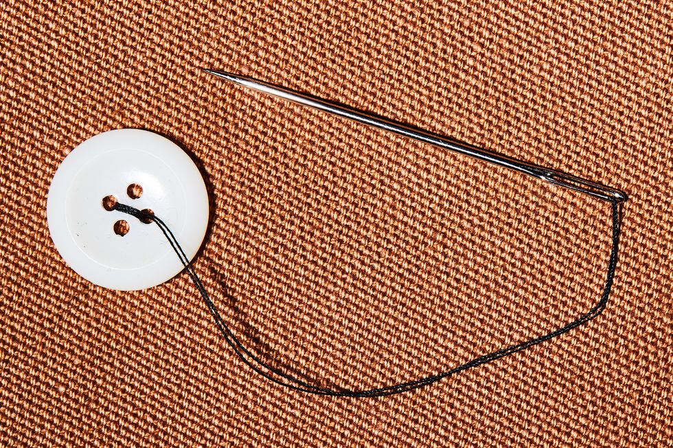 using sewing needle to sew a button