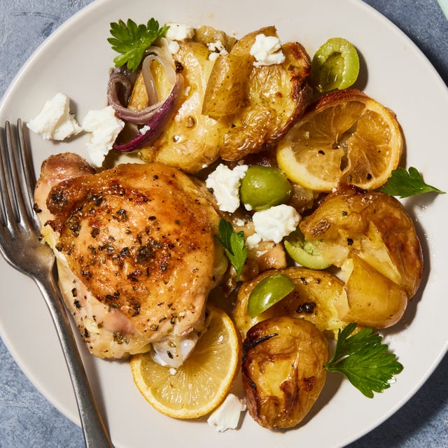 greek lemon butter chicken with smashed potatoes and olives on a sheet pan