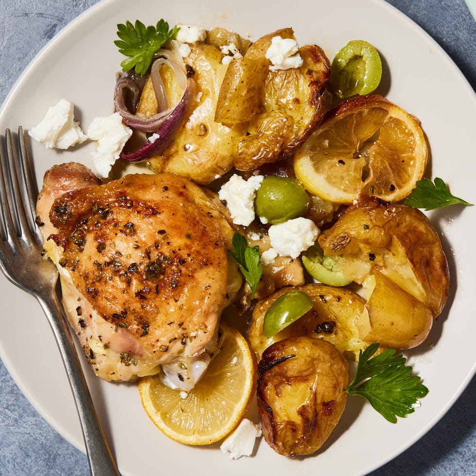 greek lemon butter chicken with smashed potatoes and olives on a sheet pan