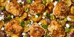 greek lemon butter chicken with smashed potatoes and olives on a sheet pan