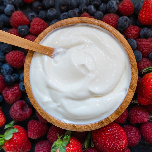 greek yogurt in a glass jars with spoons,healthy breakfast with fresh greek yogurt, muesli and berries on background