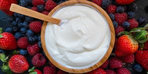 greek yogurt in a glass jars with spoons,healthy breakfast with fresh greek yogurt, muesli and berries on background