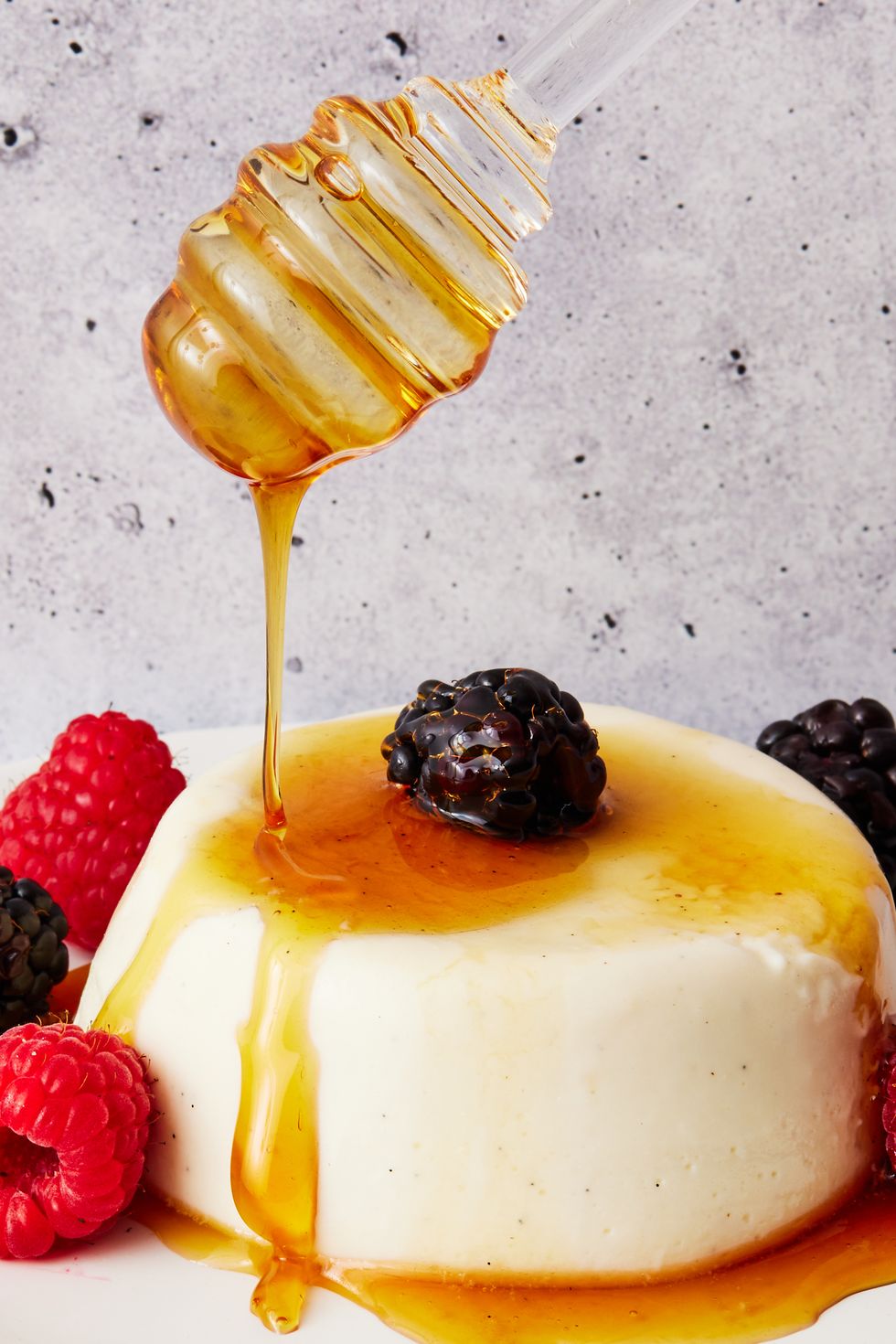 greek yogurt panna cotta topped with honey, raspberries, and blackberries