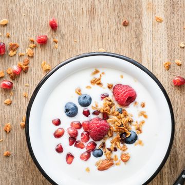 Greek yogurt with granola and berries on wooden table