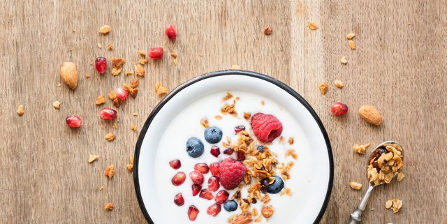 Greek yogurt with granola and berries on wooden table