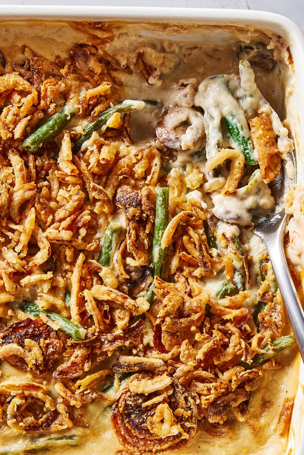 green bean casserole in a white baking dish with crunchy onions on top