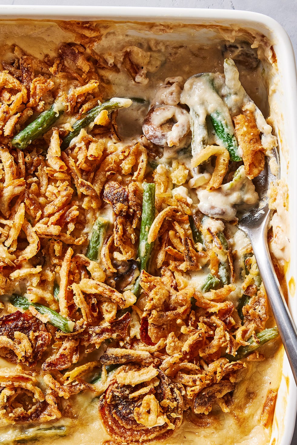 green bean casserole in a white baking dish with crunchy onions on top