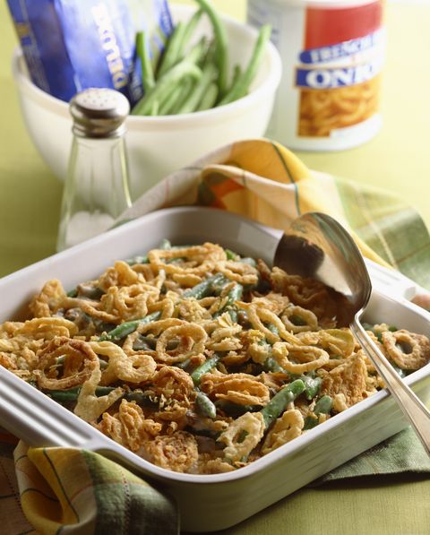 green bean casserole, topped with fried onions, with a silver spoon sitting in it