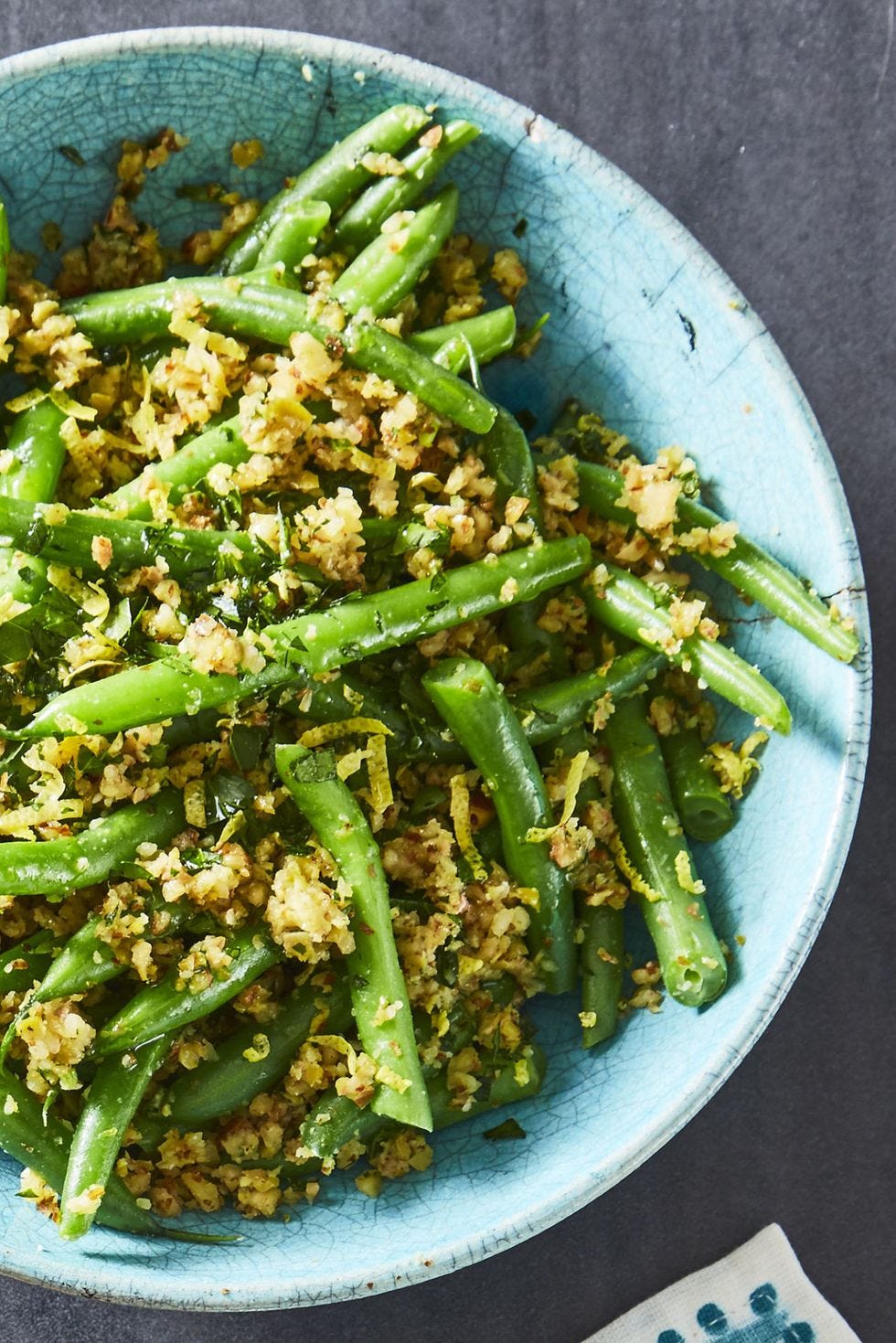 a close up of green beans with olive almond tapenade in  a blue bowl