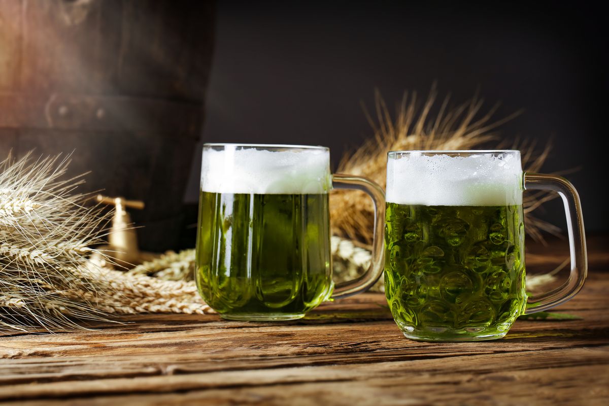 green beer on a wooden table, in the back of the original oak barrel and wheat cob this beer is traditionally served on st patrick's day, or also during easter times in europe
