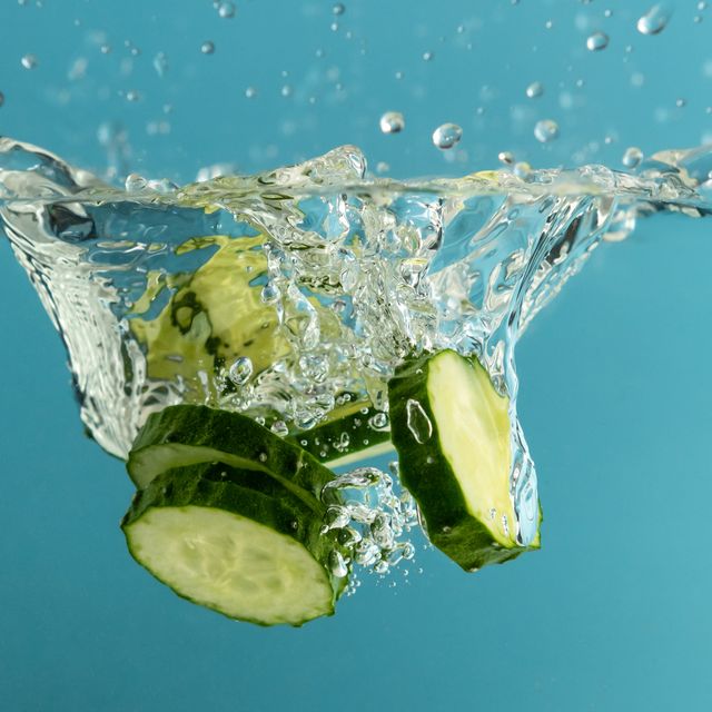 green cucumber slices in water with splash, blue background
