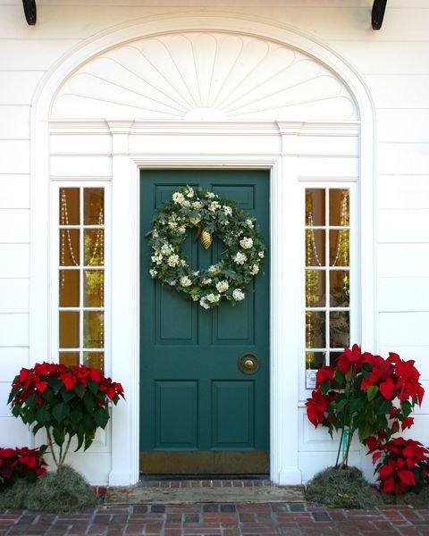 green door to a white house with a christmas wreath on it