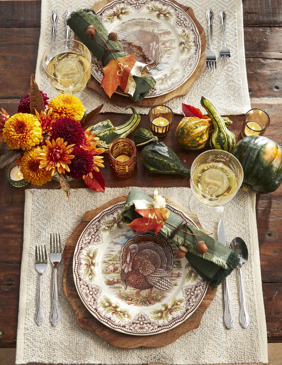 thanksgiving table with green gourds and acorn squash napkins wrapped in twine with acrons attached and a natural leaf place card painted with gold leaf