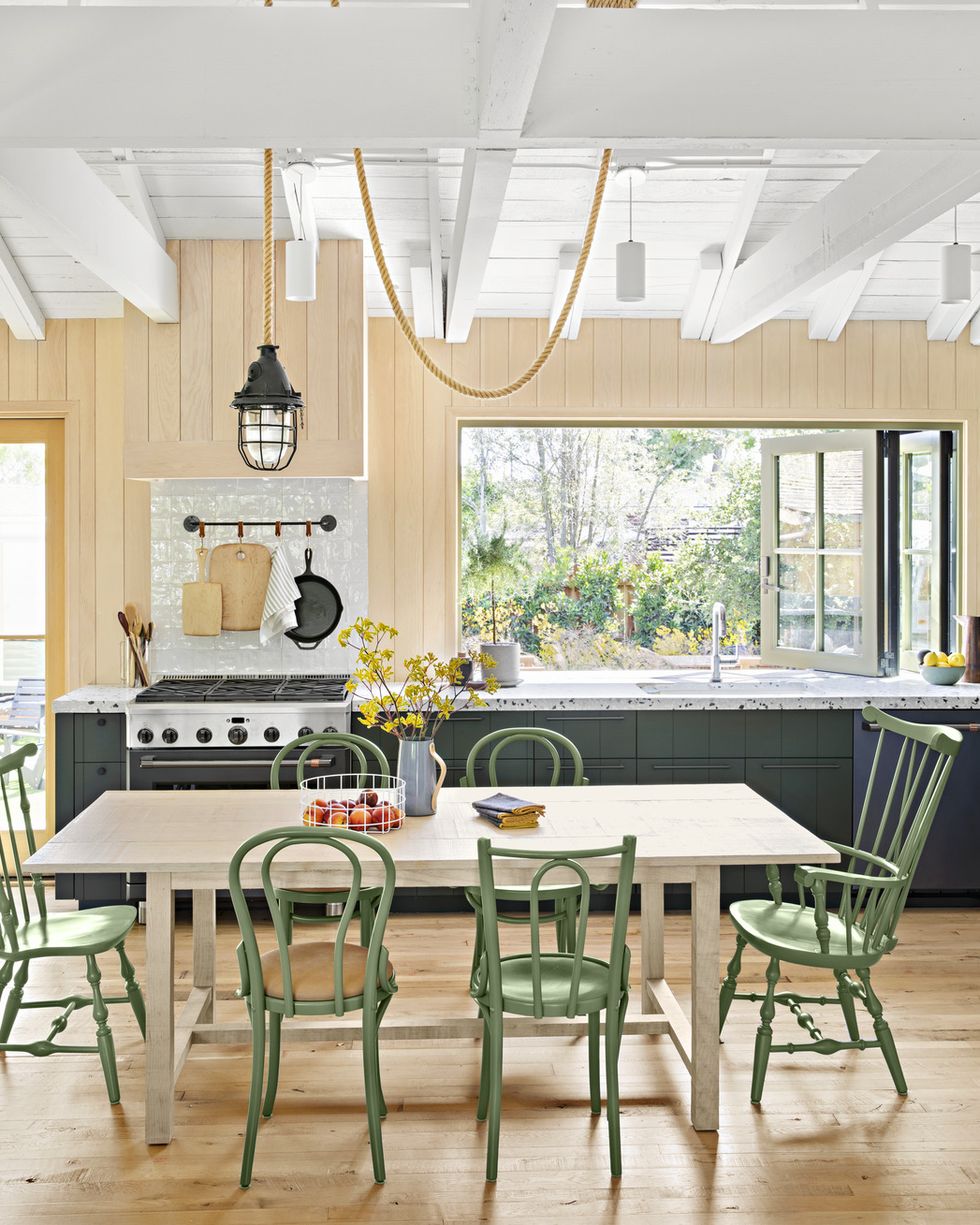 a kitchen with dark green lower cabinets and a table with green chairs in a lighter shade of green