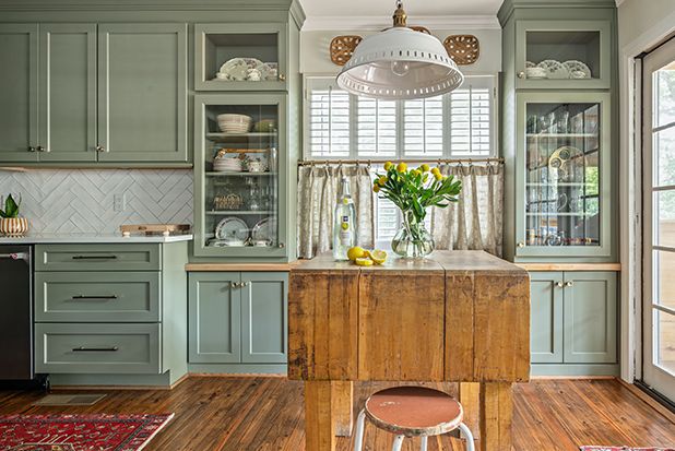 green kitchen cabinets with glass fronts and an antique butcher block island