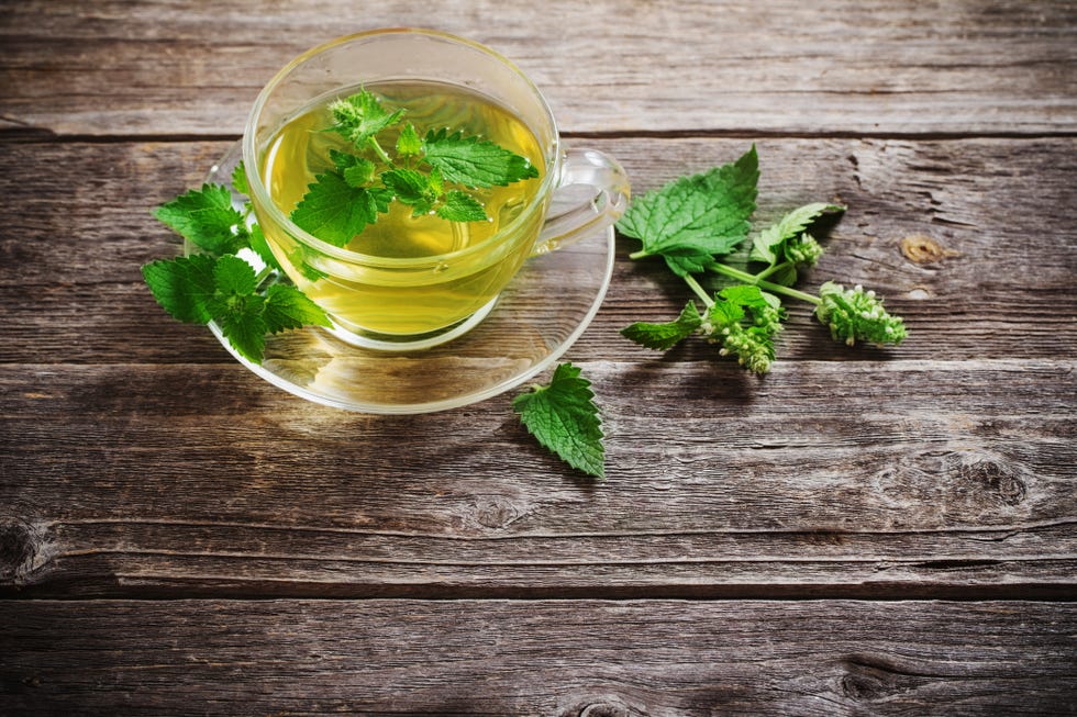 green melissa herbal tea in glass cup on wooden background