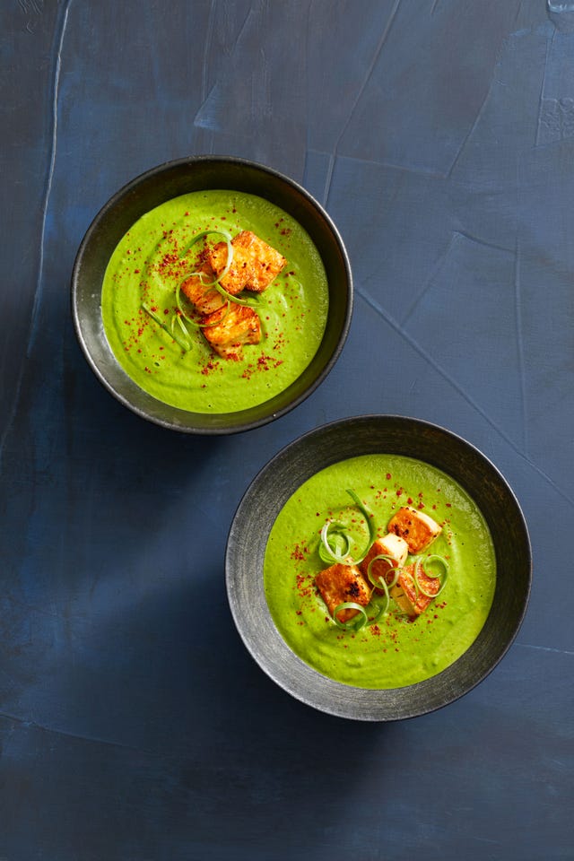 green soup with crispy tofu in a black ceramic bowl