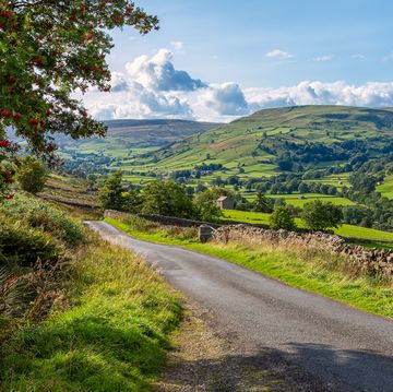 garsdale, sedbergh, yorkshire, uk august 29, 2018 scene shows hills in the yorkshire dales national park, the lush and verdant green landscape of rolling hills fills the frame man made dry stone walls are seen snaking over the landscape the scene is early afternoon, the sky is blue with white fluffy clouds on the horizon