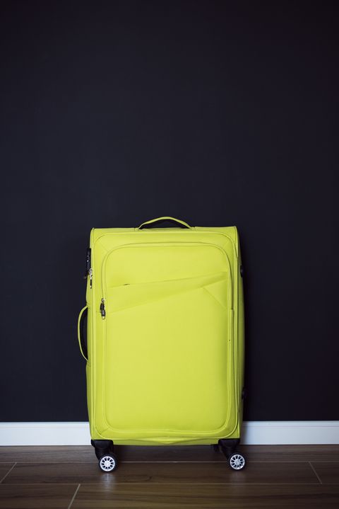 green suitcase on black wall