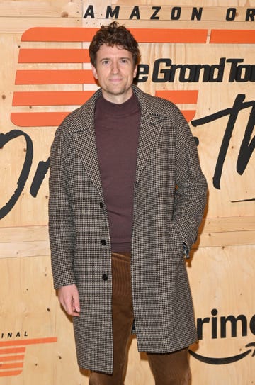 greg james in a patterned coat poses at an event backdrop