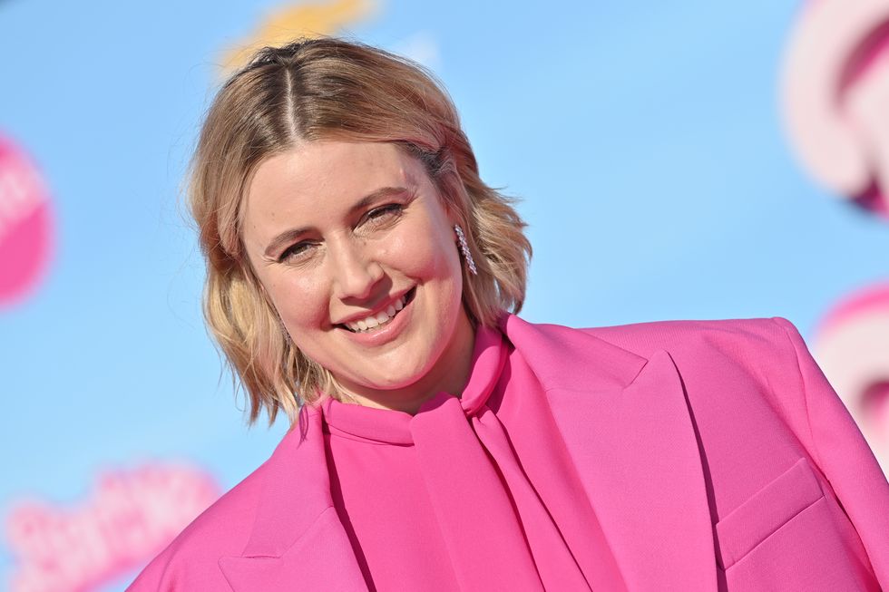 greta gerwig wearing a pink outfit and smiling