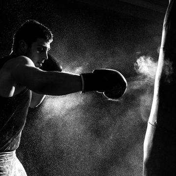 greyscale image of a boxer having a go at the punching bag