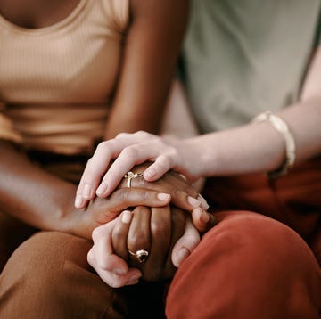two friends sitting next to each other with hands clasped together two friends sitting next to each other with hands clasped together