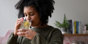 persoon drinkt een glas gemberthee om griep te voorkomen