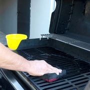person cleaning grill with sponge