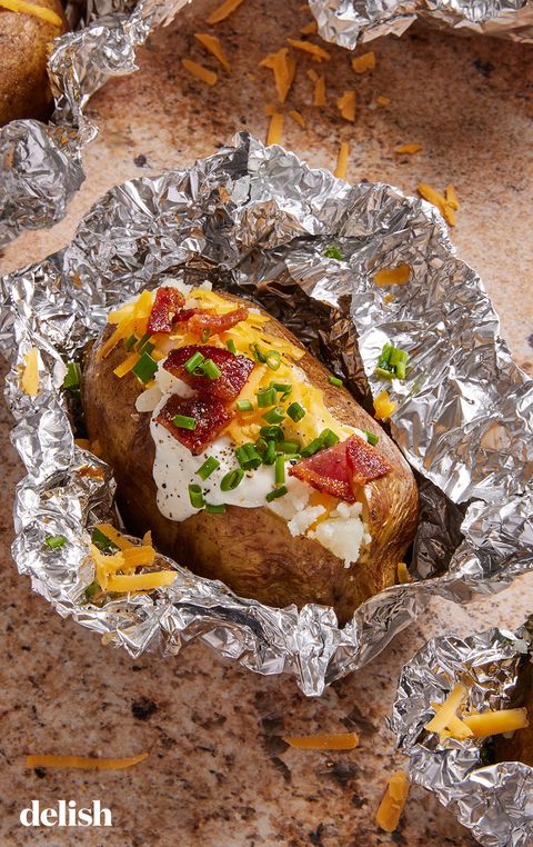 grilled baked potatoes in foil topped with bacon, sour cream, cheese, and chives