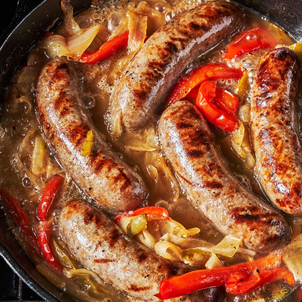 grilled bratwurst braised with beer in a pan with caramelized onions and bell peppers