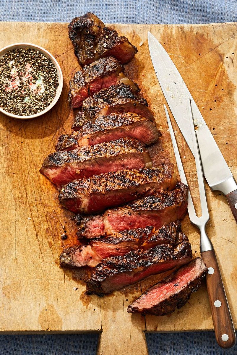 medium rare sliced rib eye steak on a wooden cutting board