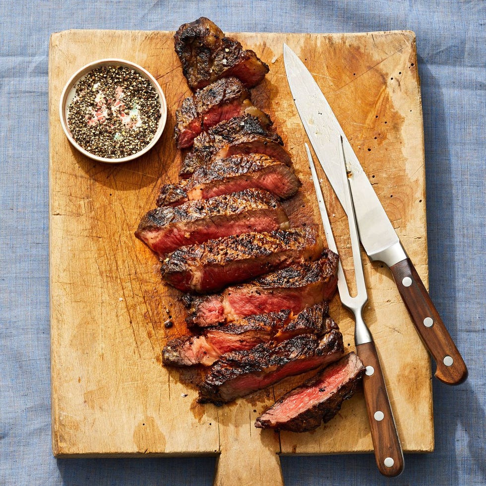 medium rare sliced rib eye steak on a wooden cutting board